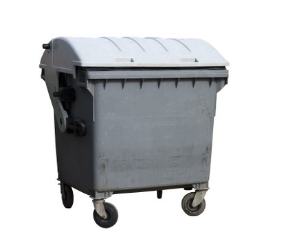 A large outdoor wheeled rubbish skip made of durable grey plastic with a fitted lid slightly curved on top, situated on a paved driveway area. The skip has four small caster wheels visible at the base for easy positioning. The surface of the bin appears slightly textured with some minor scuff marks and dirt. It is positioned in front of a building or wall that is not fully visible in the background, indicating a commercial or industrial setting typical for waste collection in Bermondsey. The environment is well-lit, suggesting daytime, with natural light highlighting the texture and form of the bin. This image reflects typical waste management equipment used by Commercial Waste Bermondsey in their rubbish removal services serving local businesses and premises within the Bermondsey postcode area, near London. The scene emphasizes the type of heavy-duty refuse containers used for bulk waste collection in the South London district by professional waste management companies.