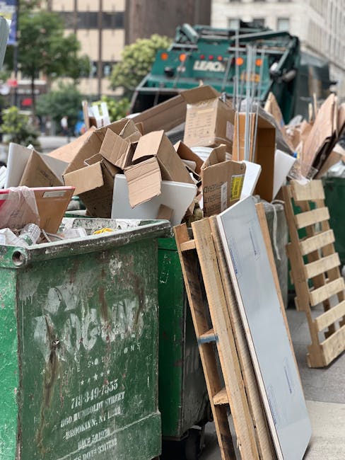 A person wearing a light blue T-shirt and black shorts, seen from behind, is holding a white plastic rubbish bag with a red zipper closure, which is partially filled with waste and debris. The individ